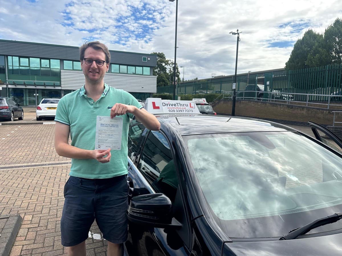 Student showing pass certificate next to DriveThruL car