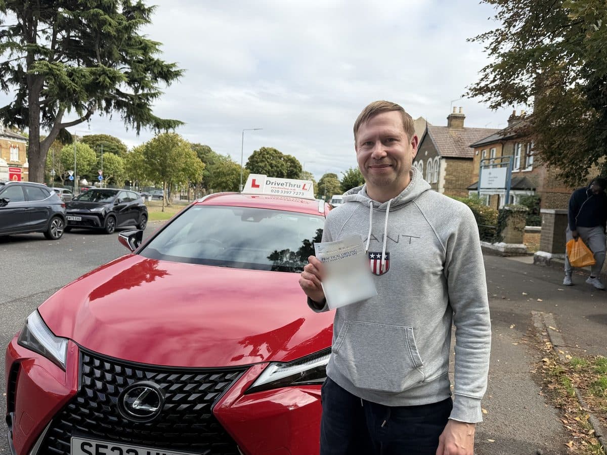A DriveThruL pupil from Canary Wharf with his pass certificate beside the driving school car, after passing at Belvedere test centre