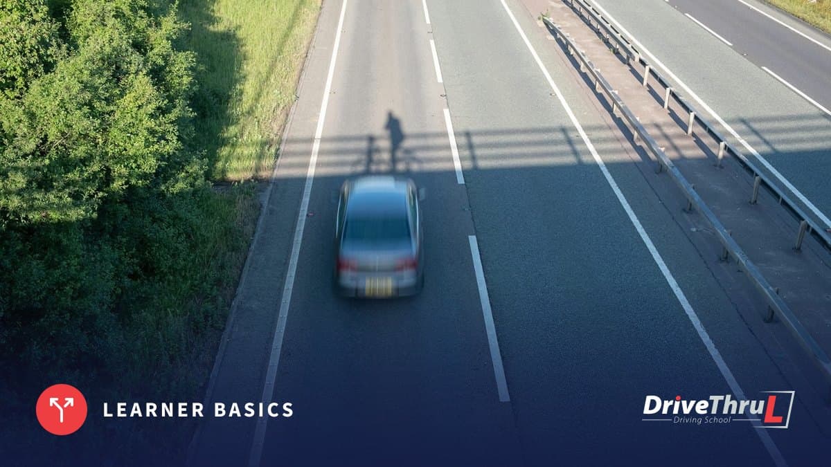 A car on a dual carriageway seen from a bridge