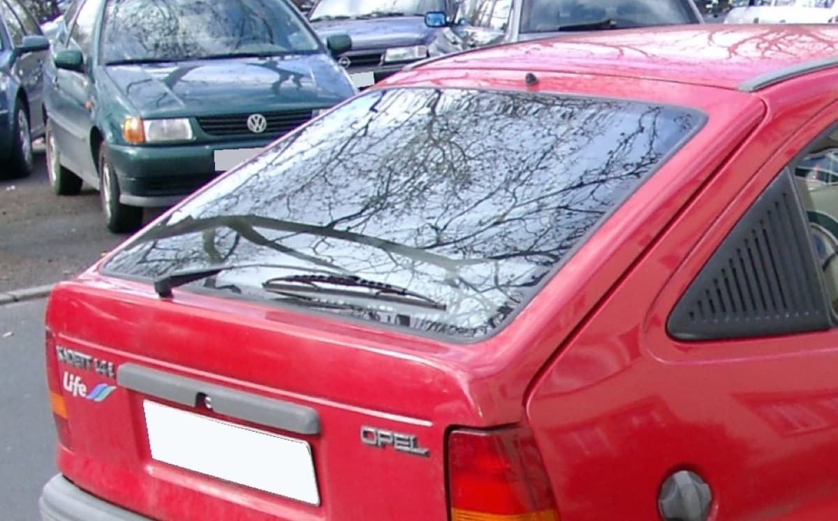 The rear windscreen and wiper of a red hatchback