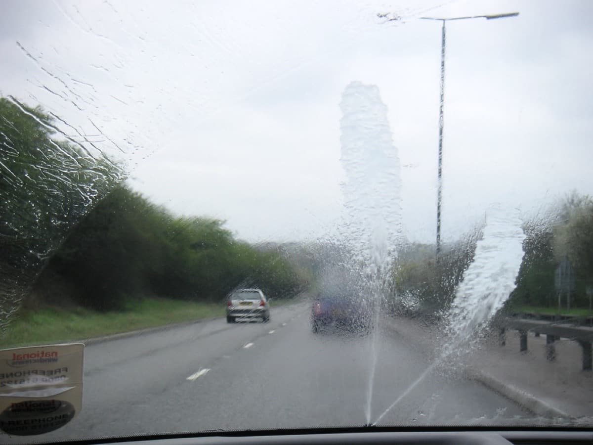 Washer jets spraying a car windscreen on a dual carriageway