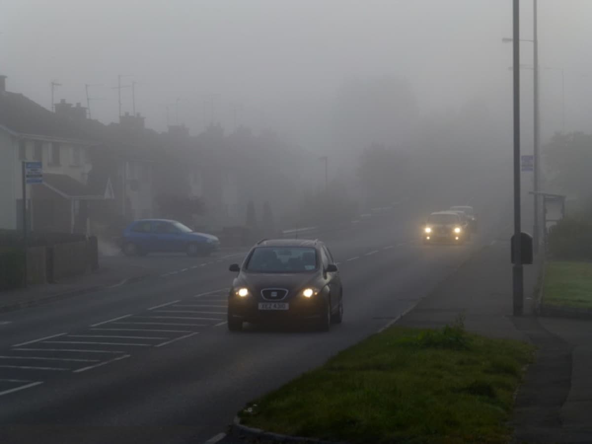 A car driving in fog with its dipped headlights on