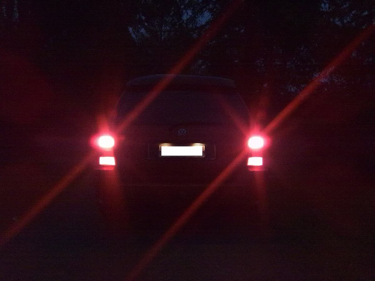 A car's brake lights glowing red at dusk