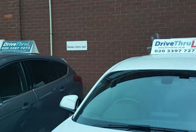 Two DriveThruL driving school cars parked at a DVSA test centre, beside a Driving Tests Only sign