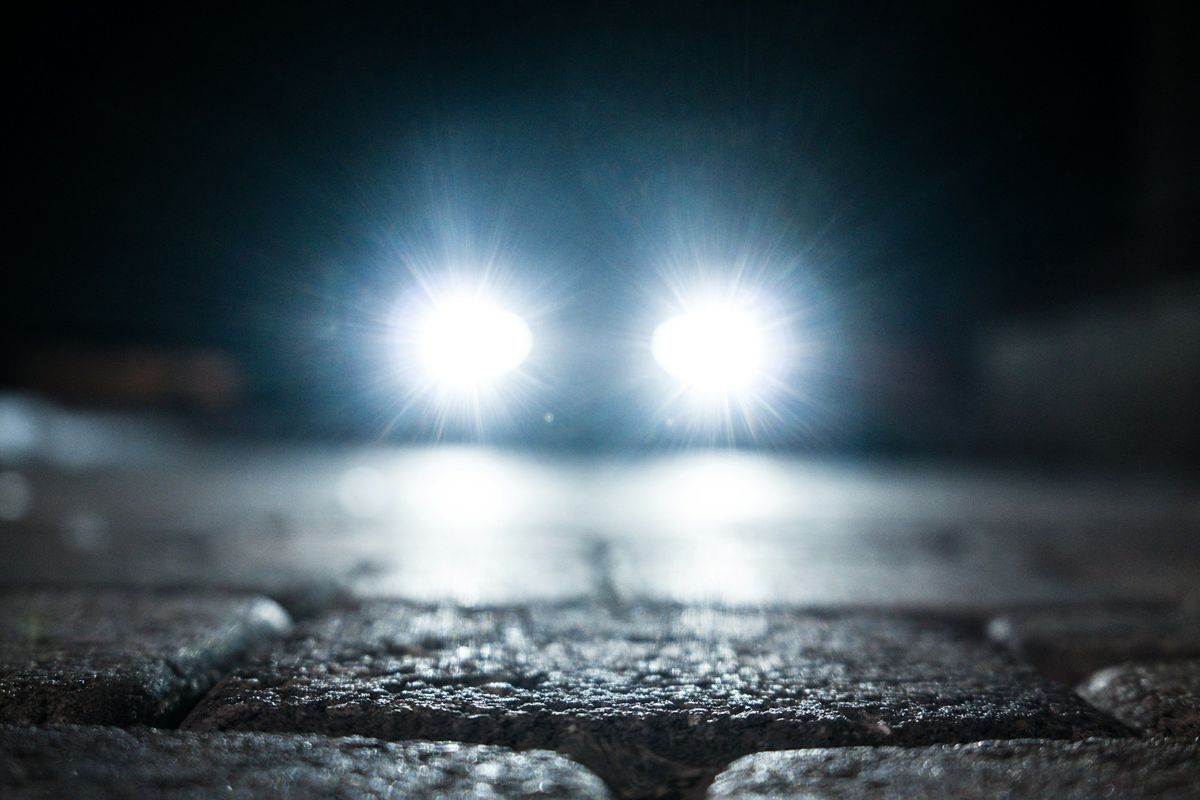 Car headlights on a wet road at night