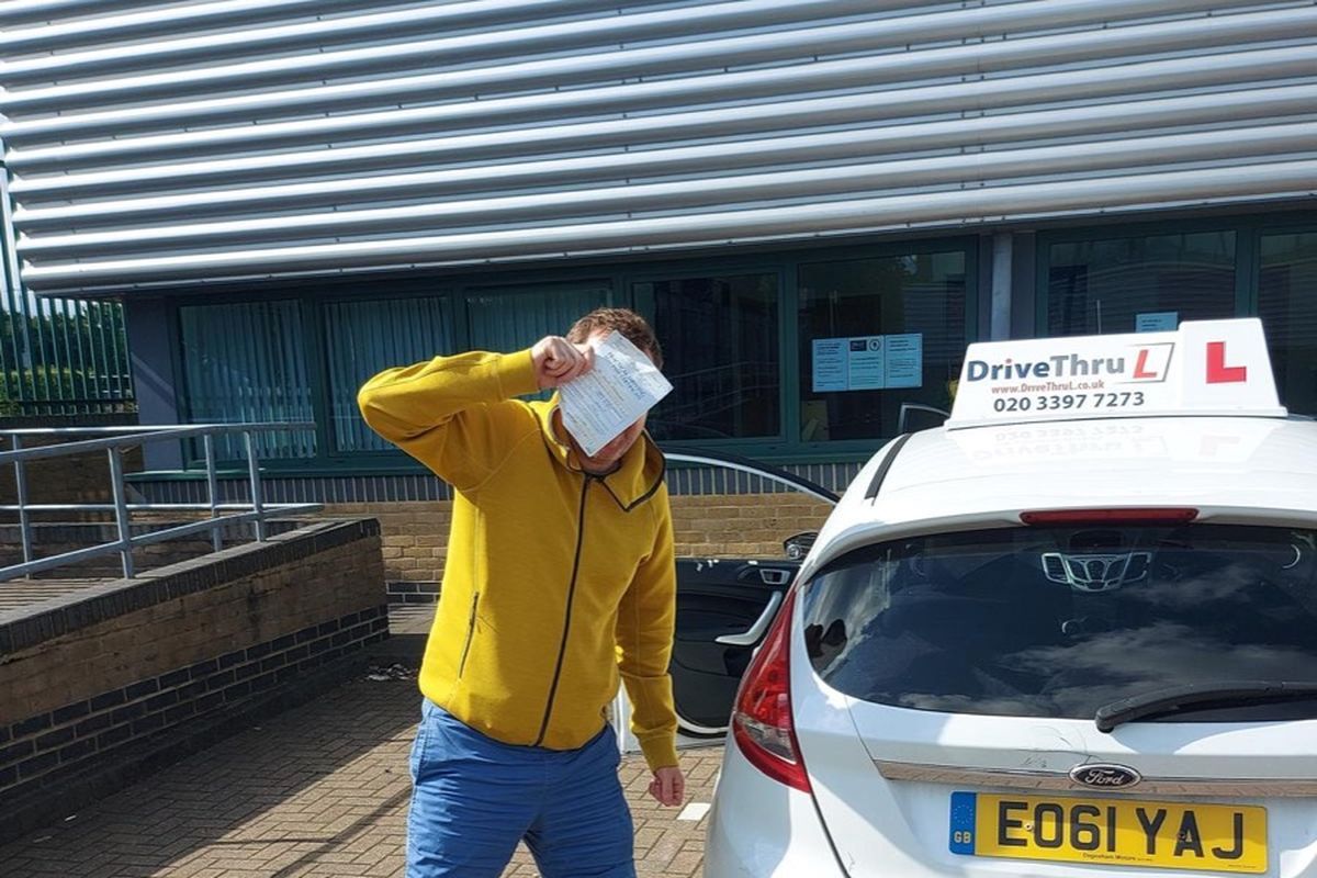 DriveThruL pupil celebrating his pass beside the car