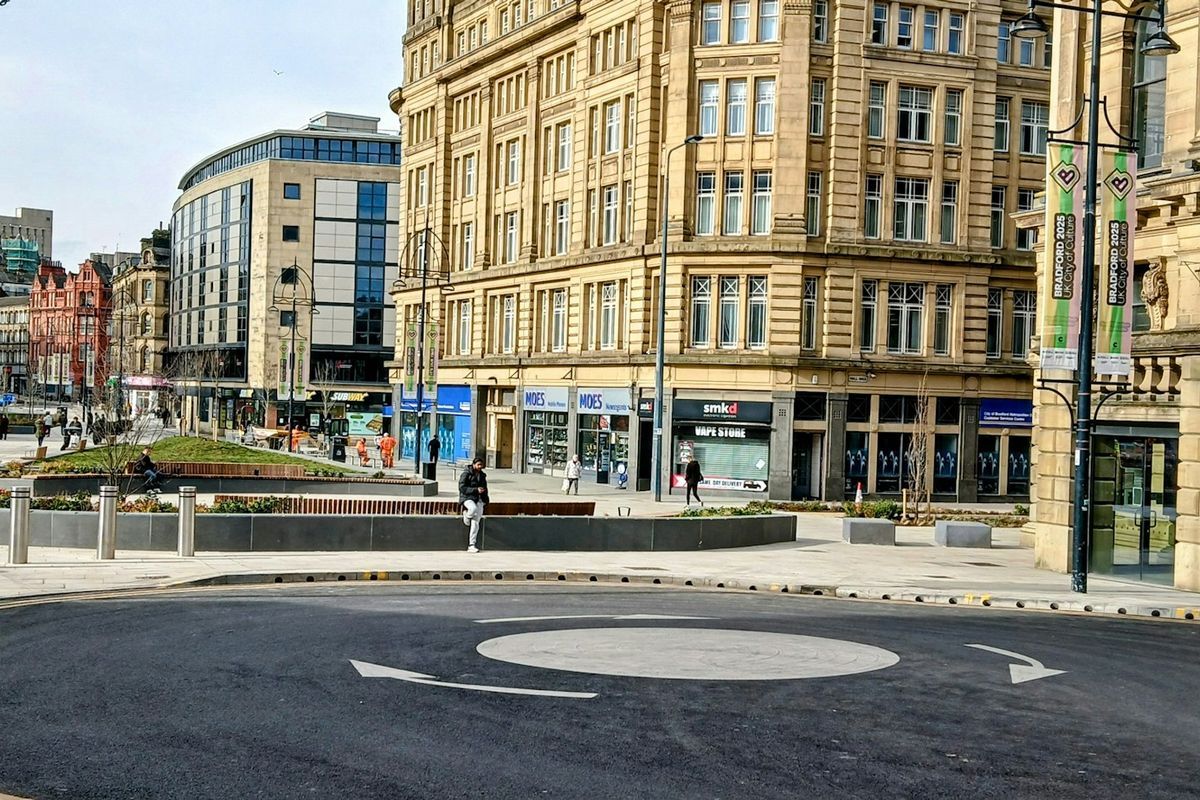 A mini roundabout painted on the road in a town centre